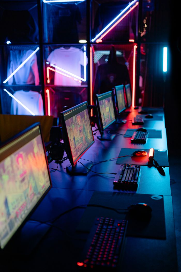 The Art of Drawing Readers In: Your attractive post title goes here A modern cybercafe setup featuring neon lights and aligned computer stations with colorful screens.